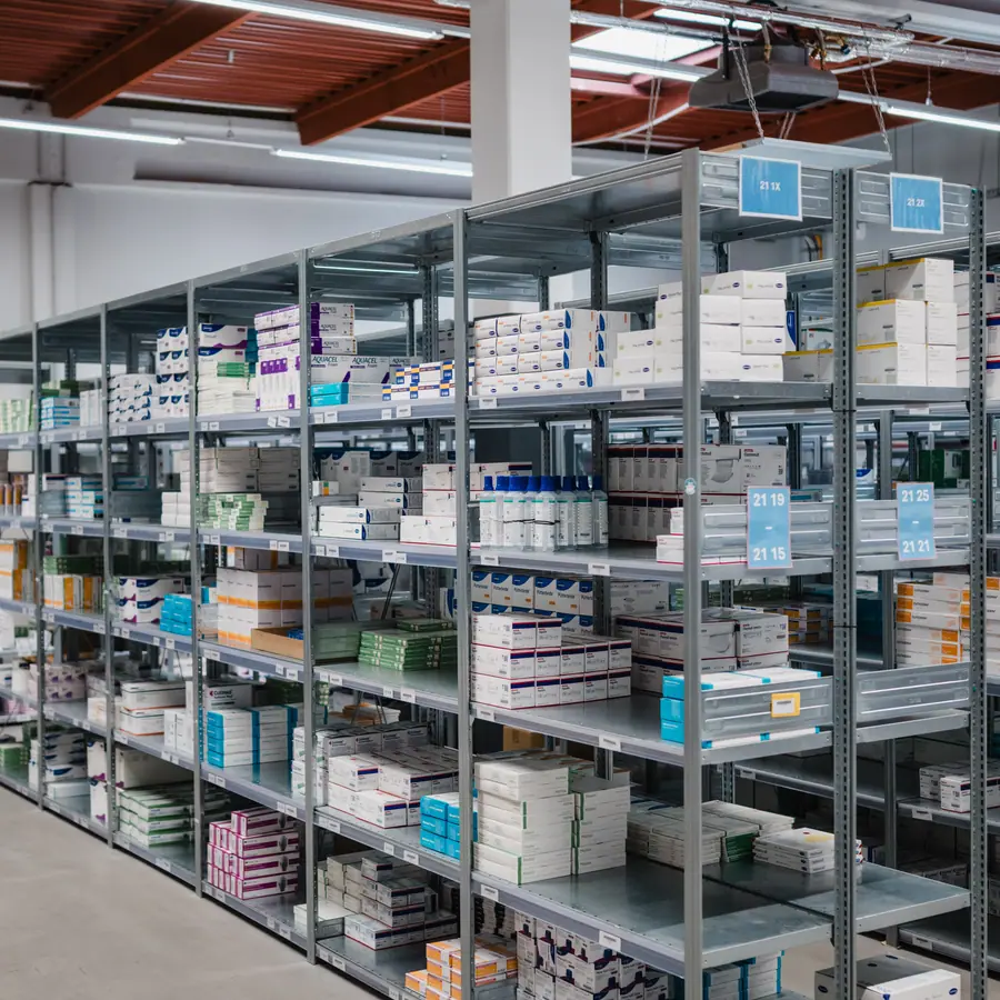 Regalreihe im Lager der adequapharm, gefüllt mit sortierten Arzneimittelpackungen